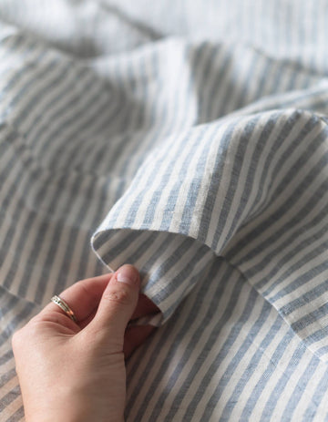 Close-up of a hand holding striped fabric with blue and white lines.