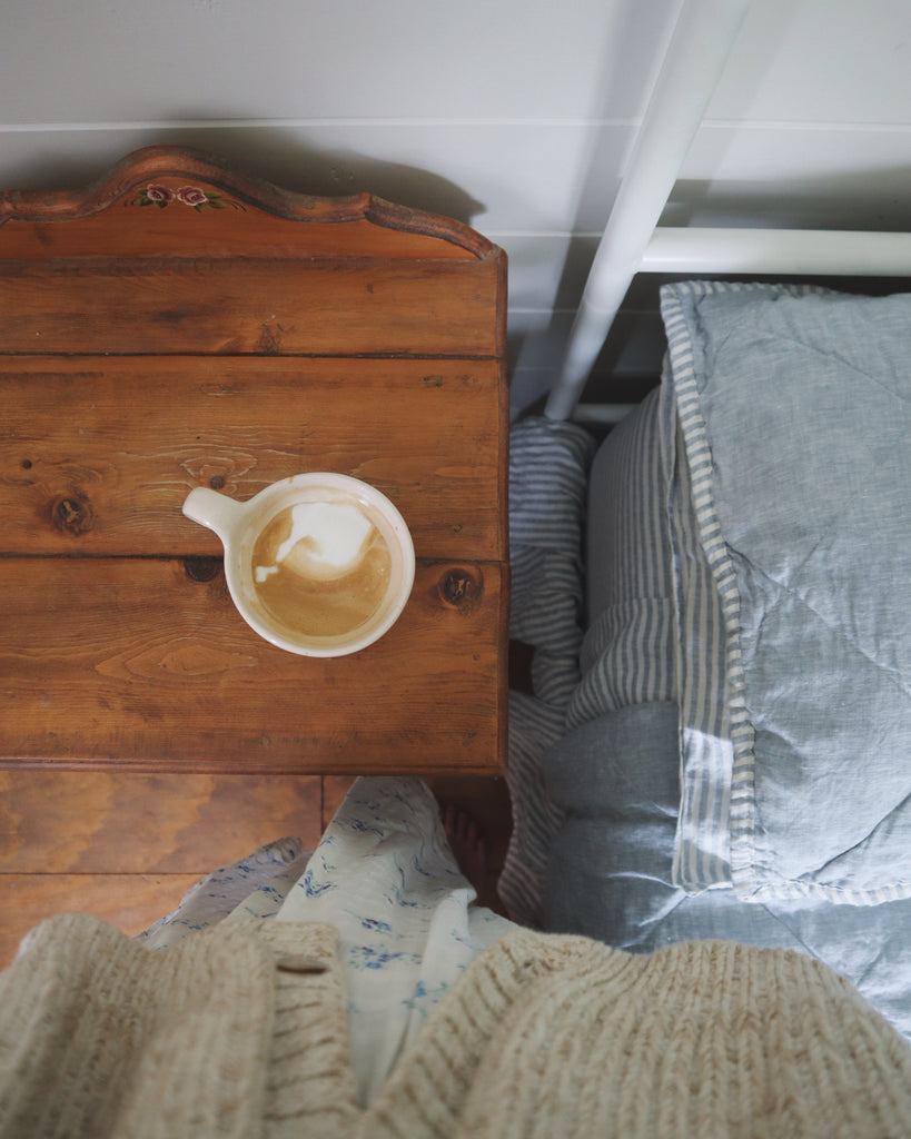 Wooden surface with a cup of coffee and a striped fabric in the background