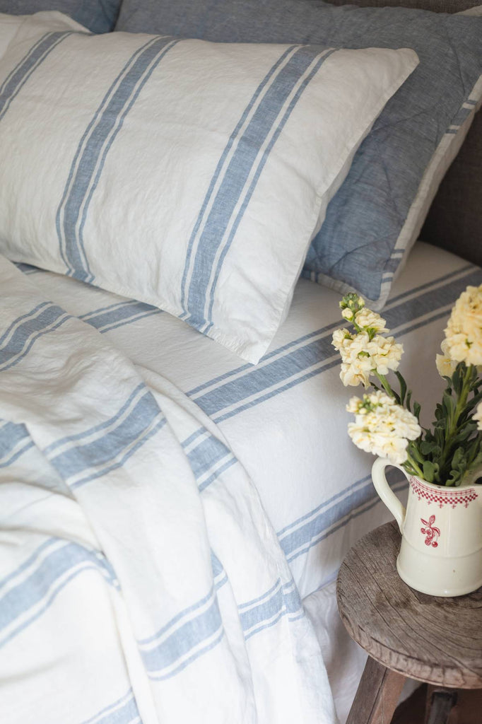 Striped bedding with a vase of flowers on a wooden table