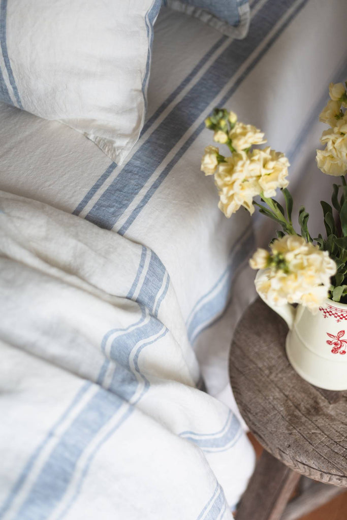 Striped fabric with a small pitcher of flowers on a wooden surface