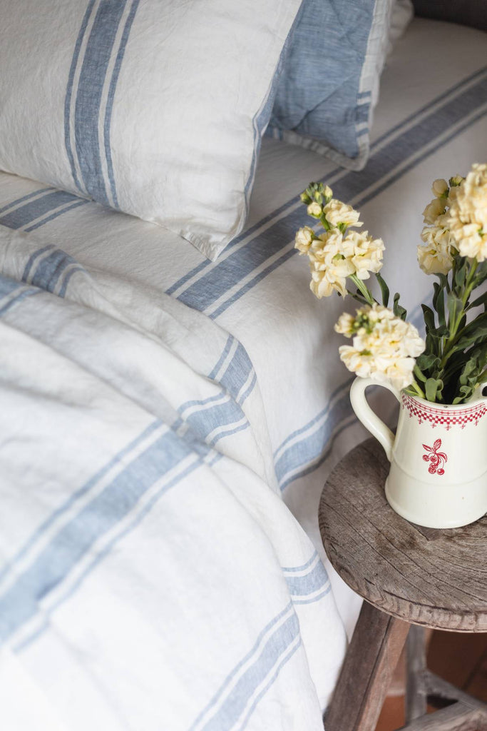 Striped bedding with a vase of flowers on a wooden table