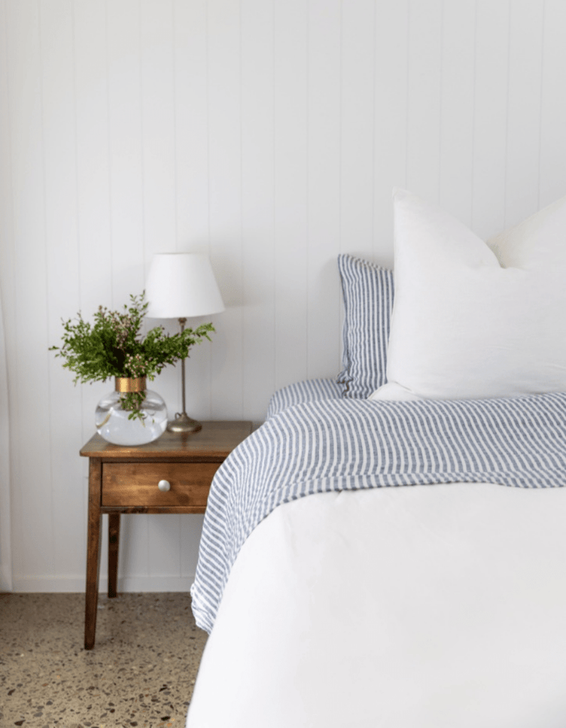 Bedroom with a bed and nightstand featuring striped bedding and a lamp.