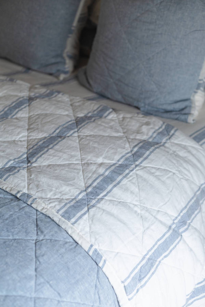 Quilt with blue and gray pattern on a bed with pillows