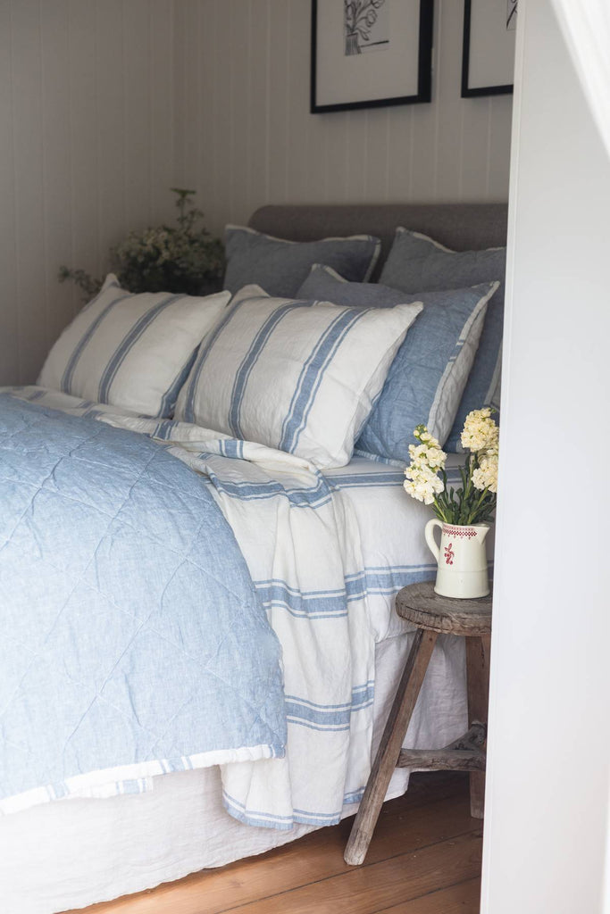 Bed with blue and white striped bedding in a bedroom setting.