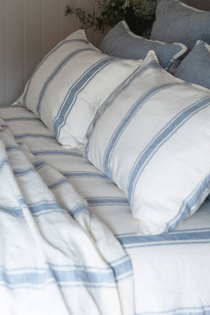 Striped bedding with blue and white lines on a bed.