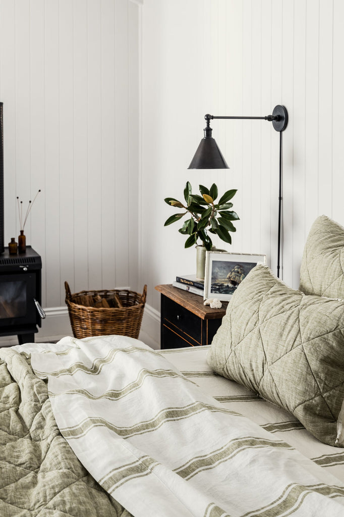 Cozy bedroom with bed, lamp, and decor items against a white wall.